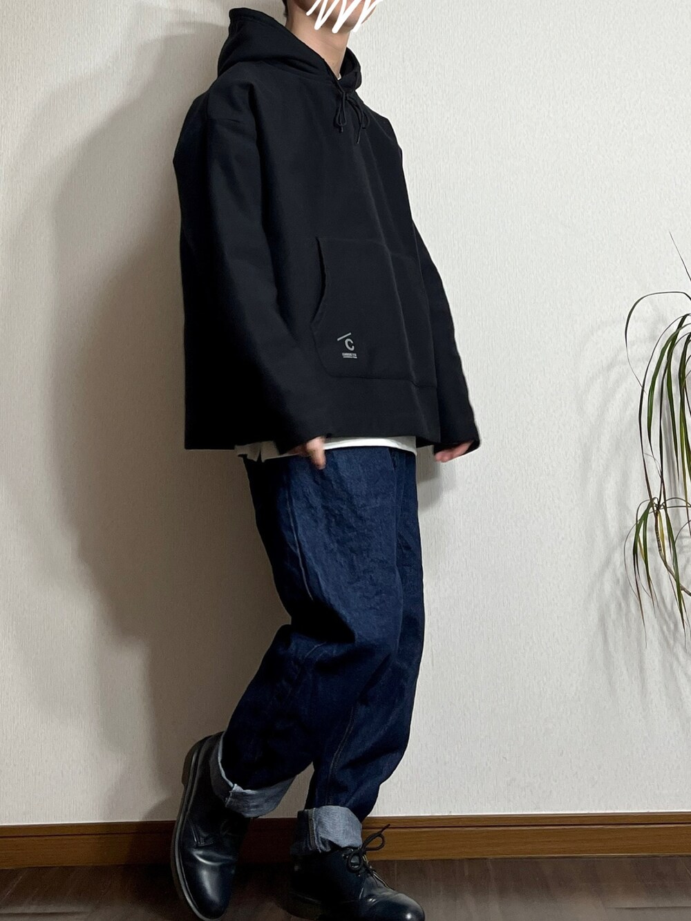 ブラック系のパーカー、ブルー系のデニムパンツ、ホワイト系のスニーカーを着用したメンズの冬コーディネートの2枚目の写真