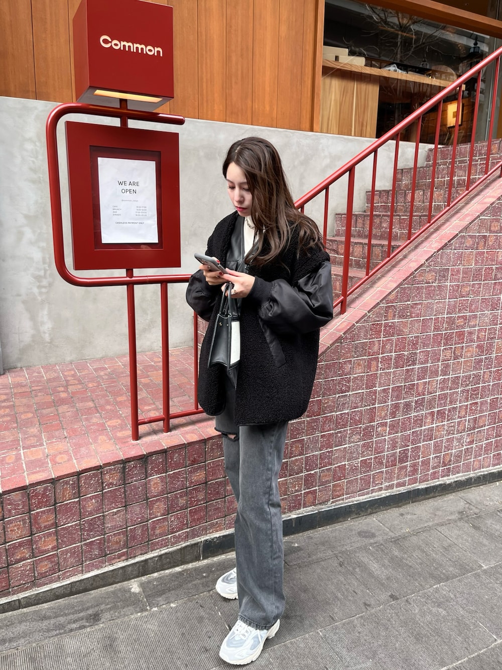 ブラック系のデニムパンツ、ホワイト系のスニーカー、ブラック系のブルゾンを着用したレディースの春コーディネートの2枚目の写真