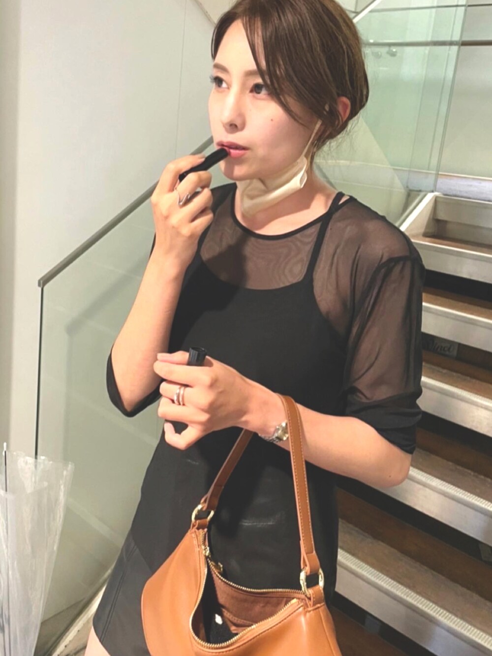 ブラウン系のハンドバッグ、ブラック系のブーツ、ブラック系のTシャツ/カットソーを着用したレディースの春コーディネートの2枚目の写真