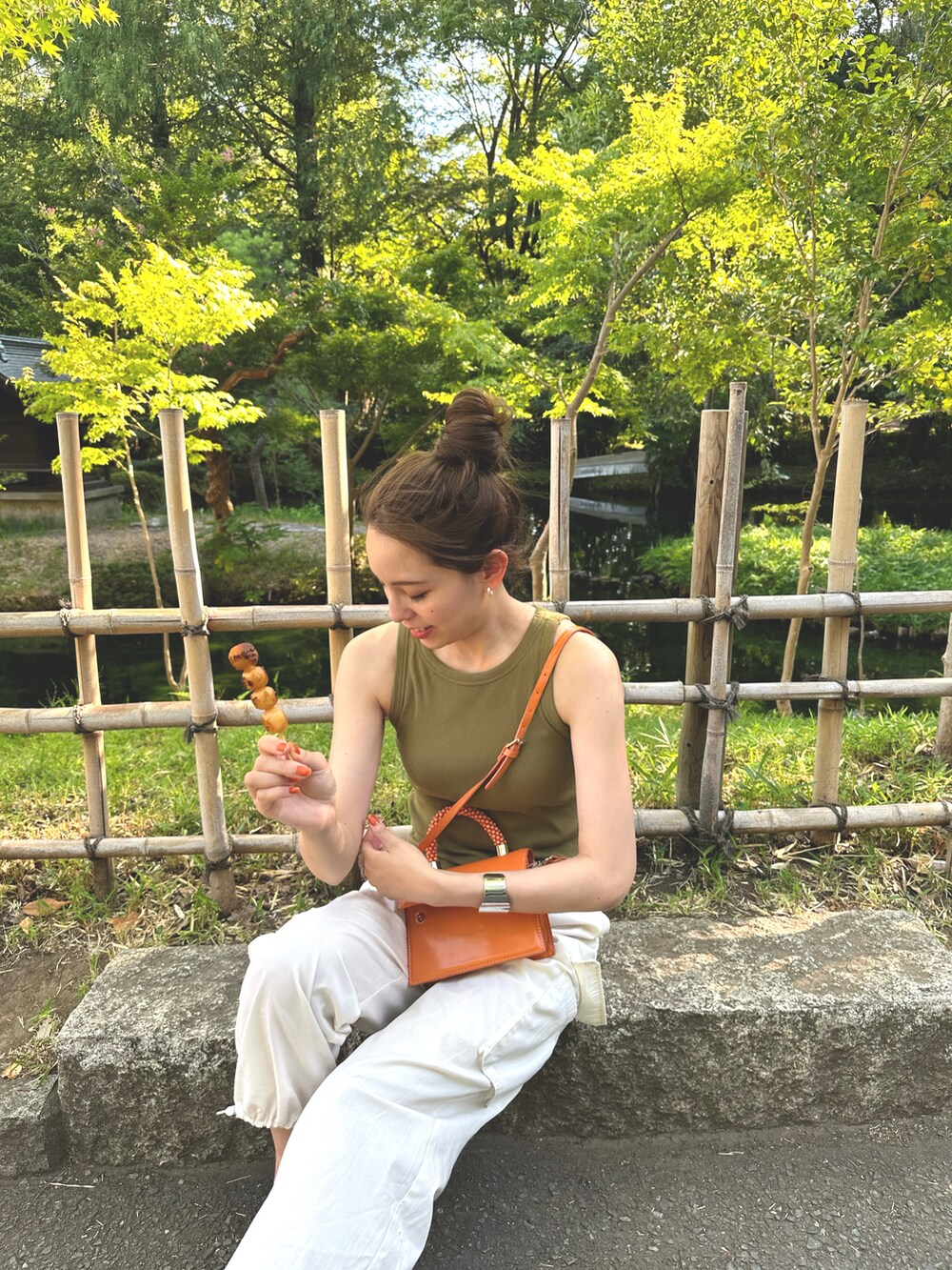 オレンジ系のバッグ、ホワイト系のカーゴパンツ、ブラウン系のサンダルを着用したレディースの夏コーディネートの2枚目の写真