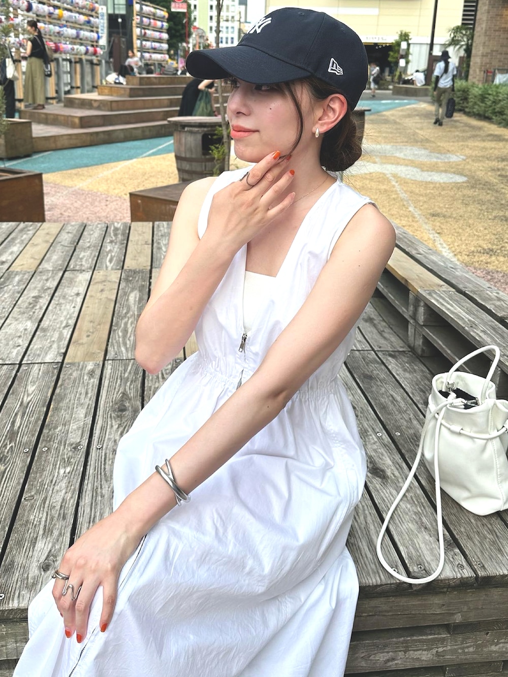 ホワイト系のワンピース、ホワイト系のサンダル、ブルー系のキャップを着用したレディースの夏コーディネートの2枚目の写真