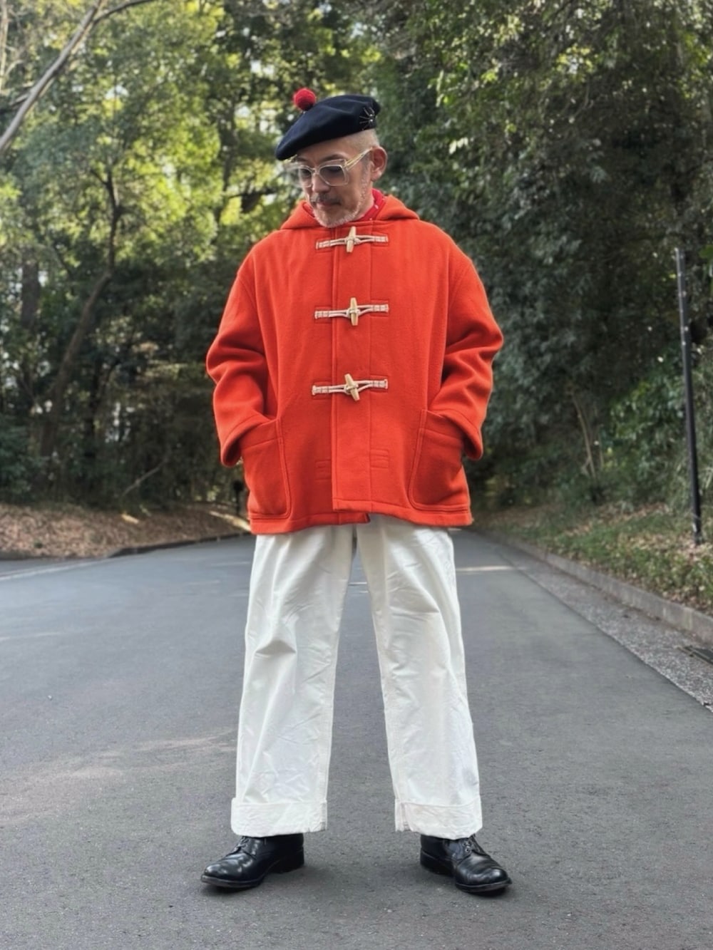 オレンジ系のダッフルコート、ホワイト系のサロペット/オーバーオール、ブラック系のブーツを着用したメンズの春コーディネートの2枚目の写真