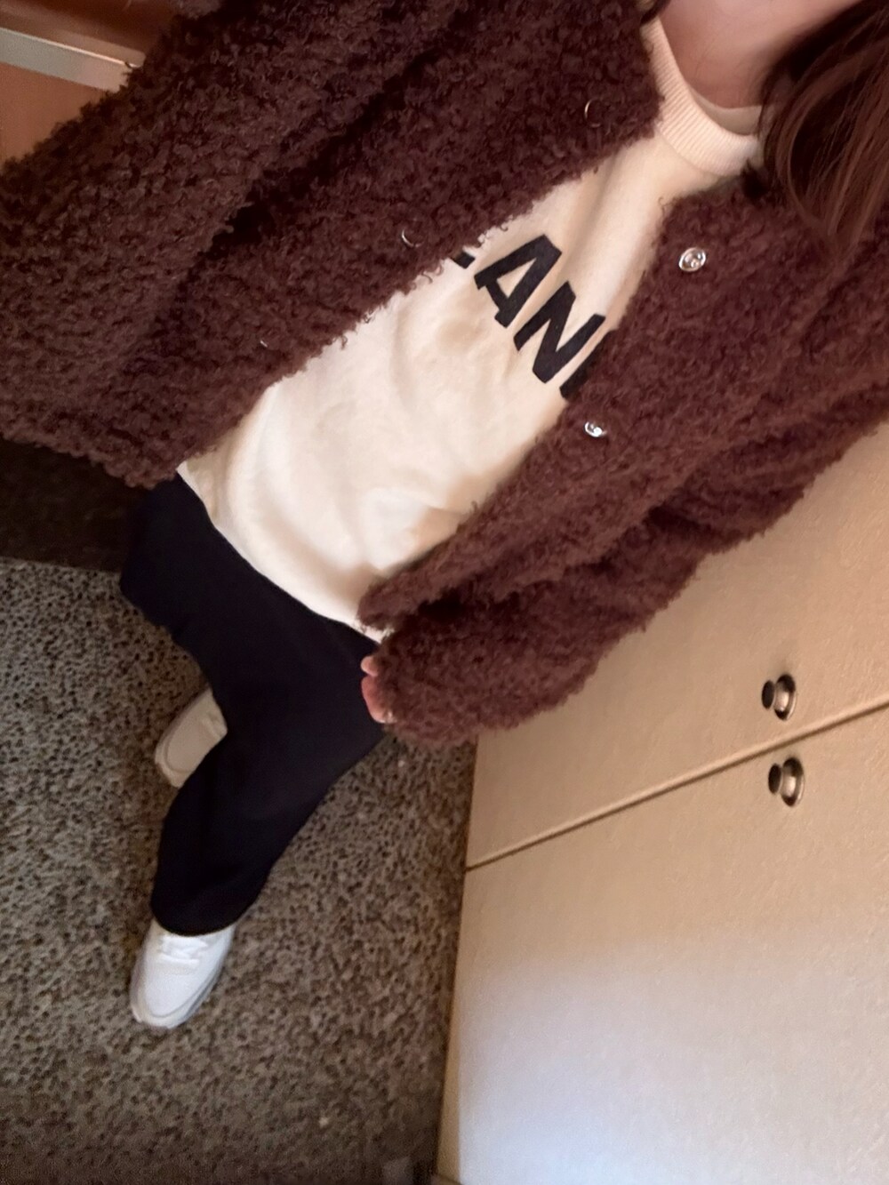 ホワイト系のスウェット、ブラック系のスカート、ホワイト系のスニーカーを着用したレディースの冬コーディネートの2枚目の写真