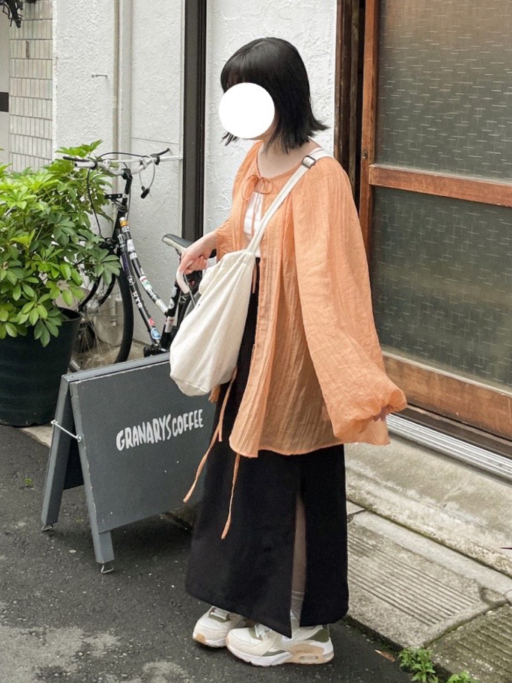 ベージュ系のトートバッグ、ブラック系のスカート、グリーン系のスニーカーを着用したレディースの夏コーディネートの2枚目の写真