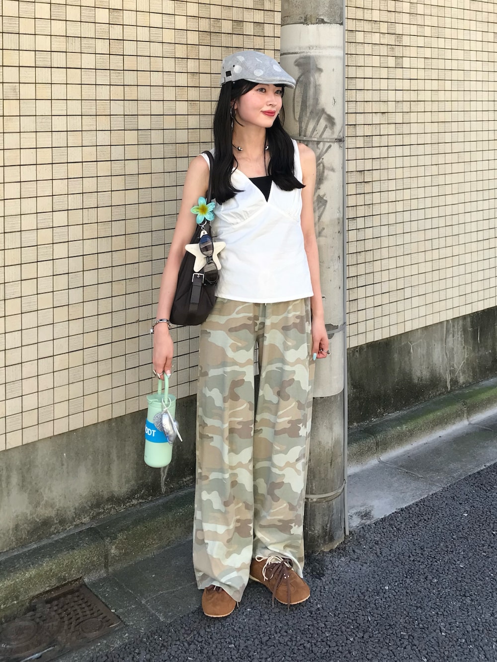 ブラウン系のスニーカー、ブラウン系のバッグ、グレー系のハンチング/ベレー帽を着用したレディースの夏コーディネートの2枚目の写真