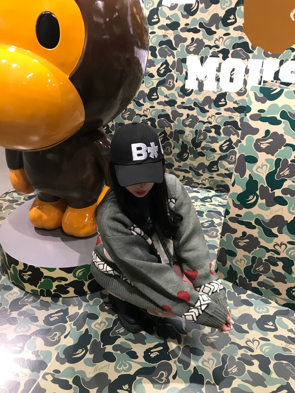 グレー系のカーディガン/ボレロ、ブラック系のブーツ、ブラック系のキャップを着用したレディースの秋コーディネートの2枚目の写真