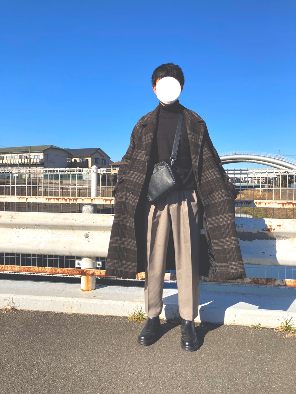 ブラック系のブーツ、ベージュ系のスラックス、ブラック系のニット/セーターを着用したメンズの冬コーディネートの2枚目の写真