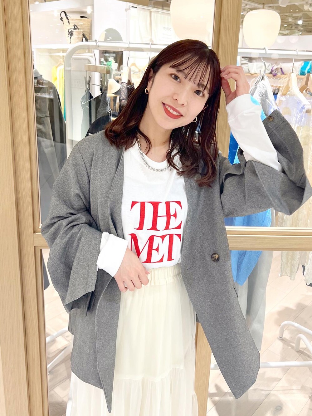 ホワイト系のTシャツ/カットソー、グレー系のノーカラージャケット、ホワイト系のスカートを着用したレディースの春コーディネートの2枚目の写真