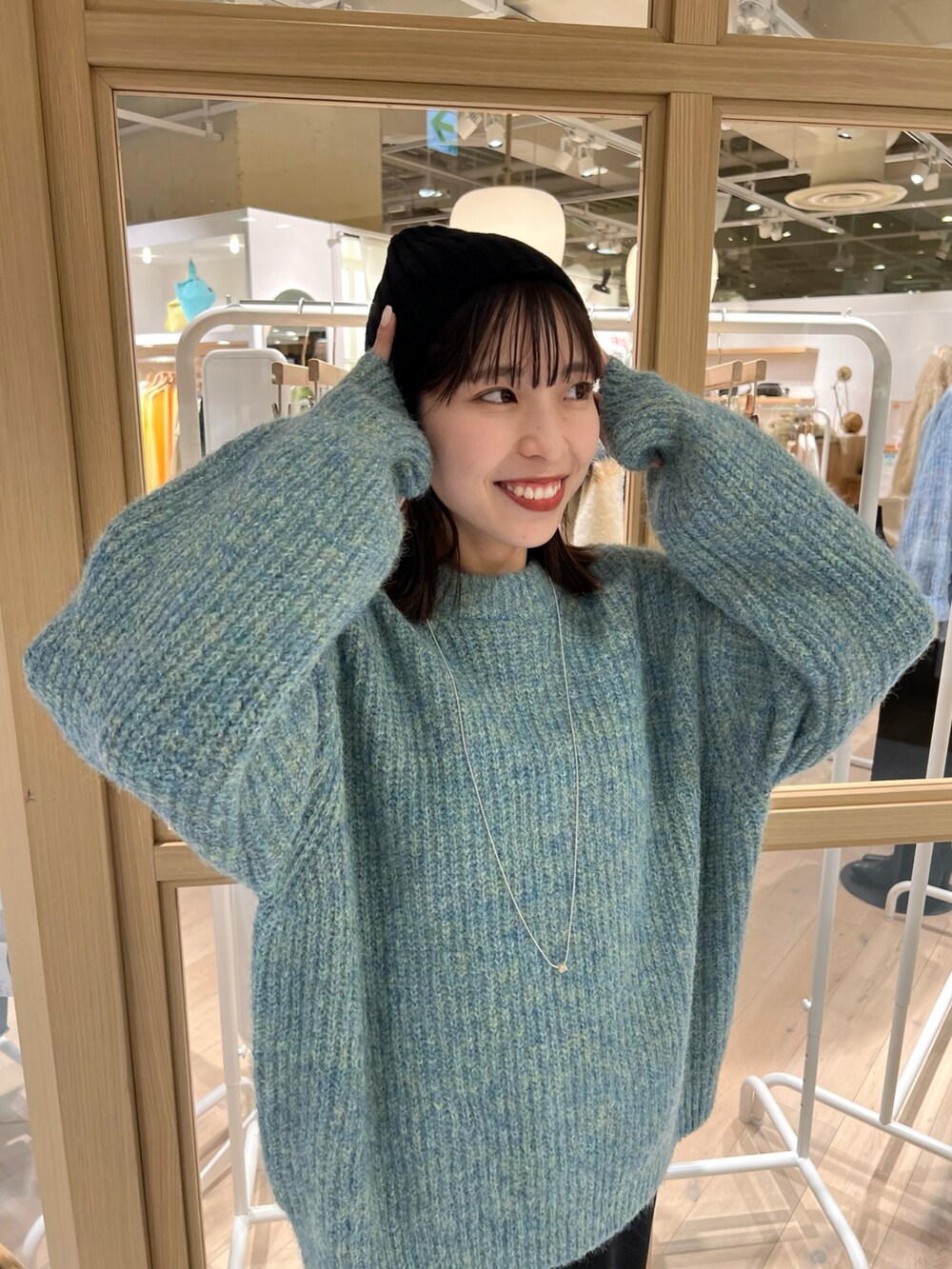 ブルー系のニット/セーター、ブラック系のワンピース、ブラック系のブーツを着用したレディースの秋コーディネートの4枚目の写真