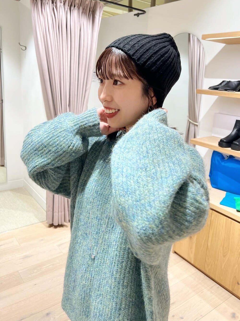 ブルー系のニット/セーター、ブラック系のワンピース、ブラック系のブーツを着用したレディースの秋コーディネートの3枚目の写真