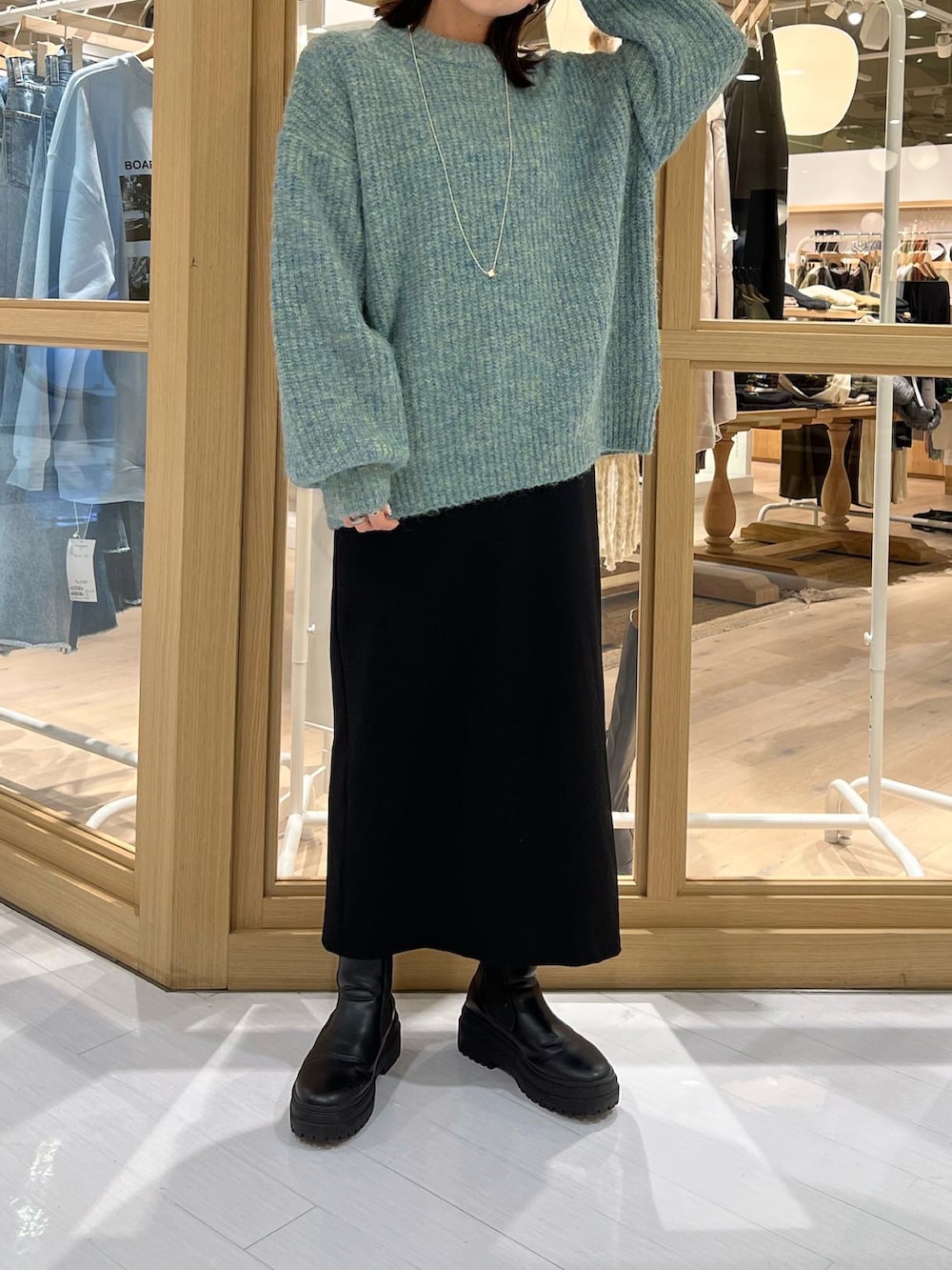 ブルー系のニット/セーター、ブラック系のワンピース、ブラック系のブーツを着用したレディースの秋コーディネートの2枚目の写真