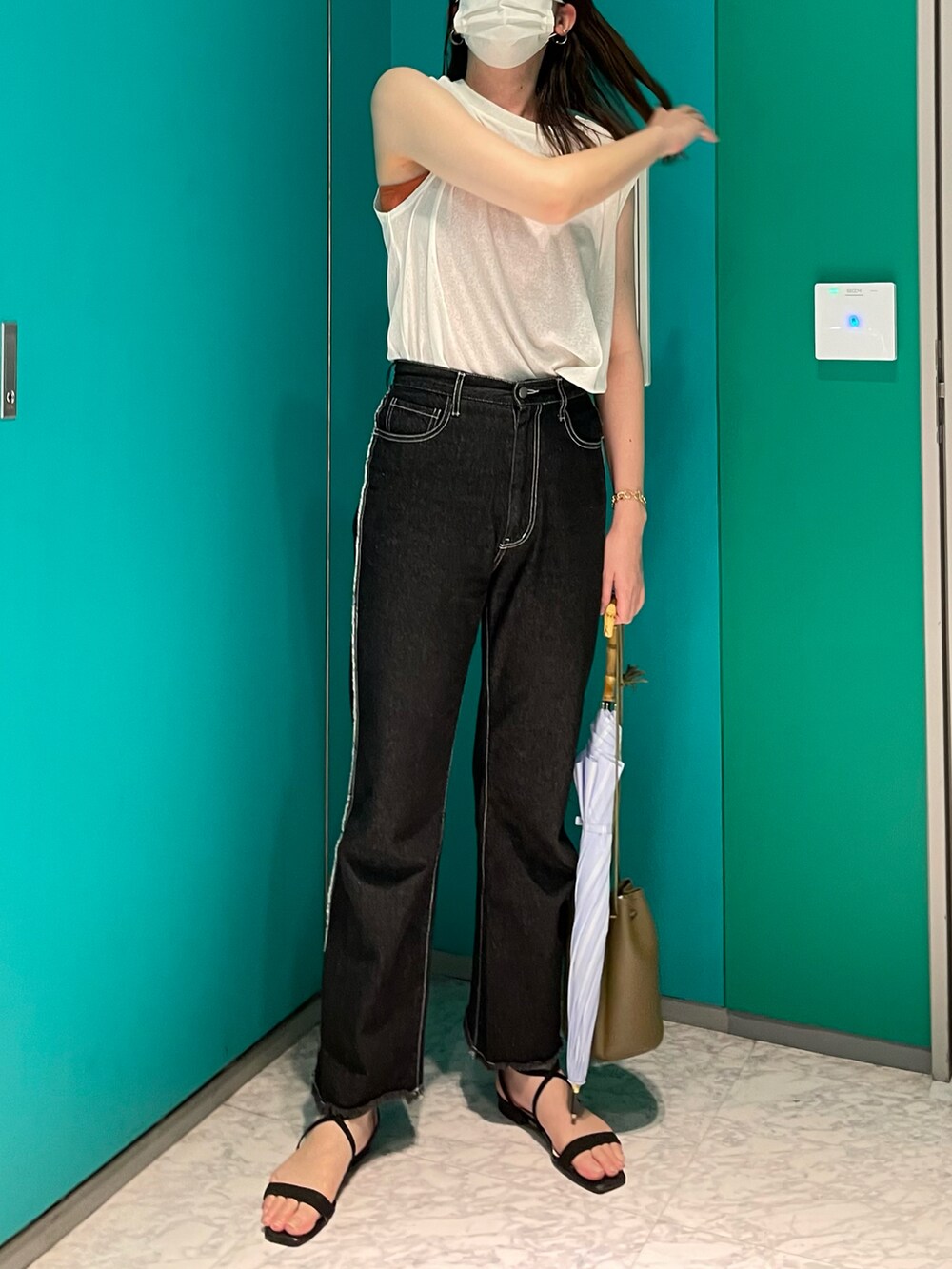 ホワイト系のトップス、グリーン系のショルダーバッグ、ブラック系のデニムパンツを着用したレディースの夏コーディネートの2枚目の写真