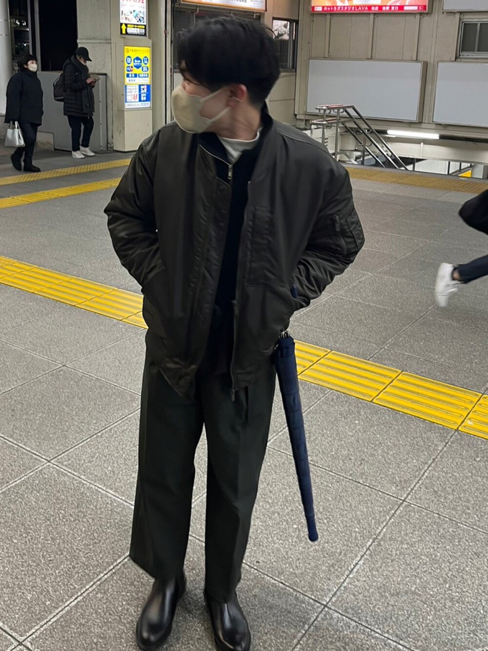 グリーン系のMA-1、ブラック系のニット/セーター、グレー系のスラックスを着用したメンズの冬コーディネートの2枚目の写真