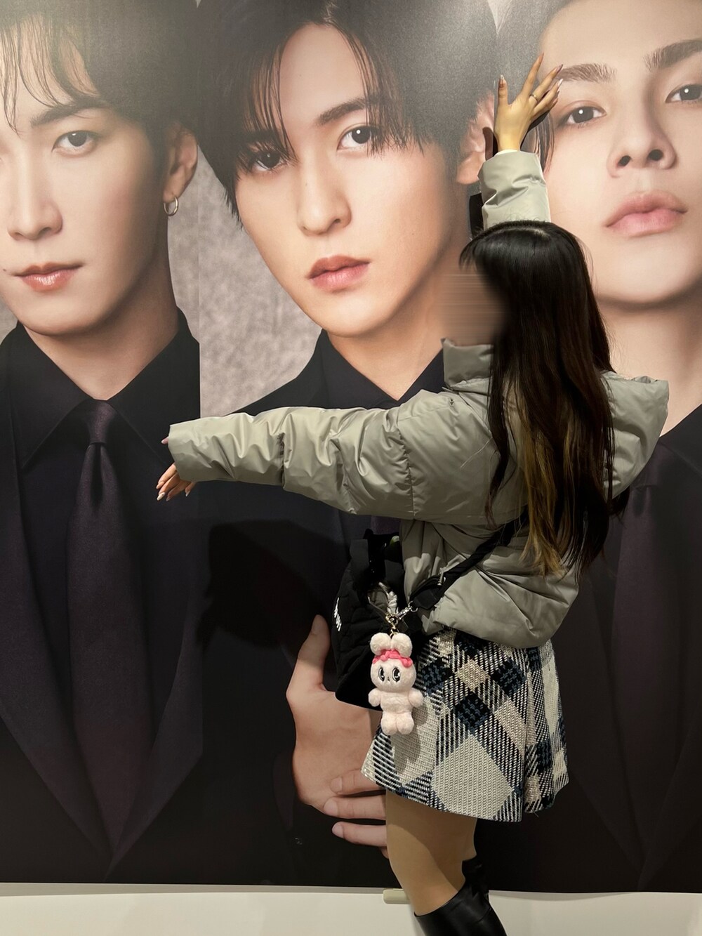 グレー系のダウンジャケット/コート、ブラック系のショルダーバッグ、ホワイト系のスカートを着用したレディースの冬コーディネートの2枚目の写真