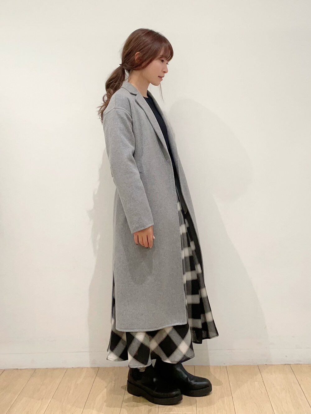 ブラック系のニット/セーター、グレー系のチェスターコート、ブラック系のスカートを着用したレディースの冬コーディネートの2枚目の写真