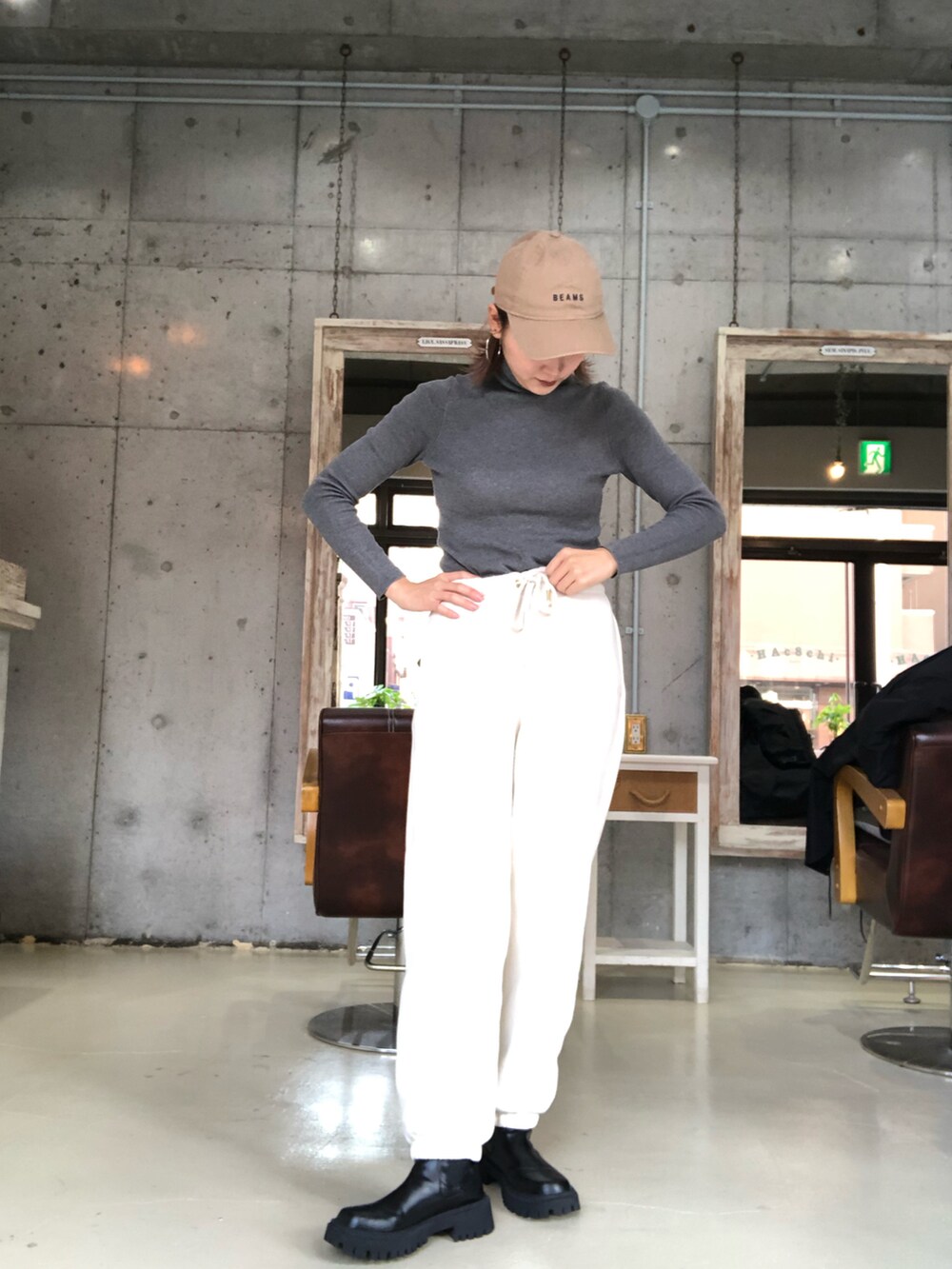 ブラック系のモッズコート、グレー系のトップス、ベージュ系のキャップを着用したレディースの秋コーディネートの2枚目の写真