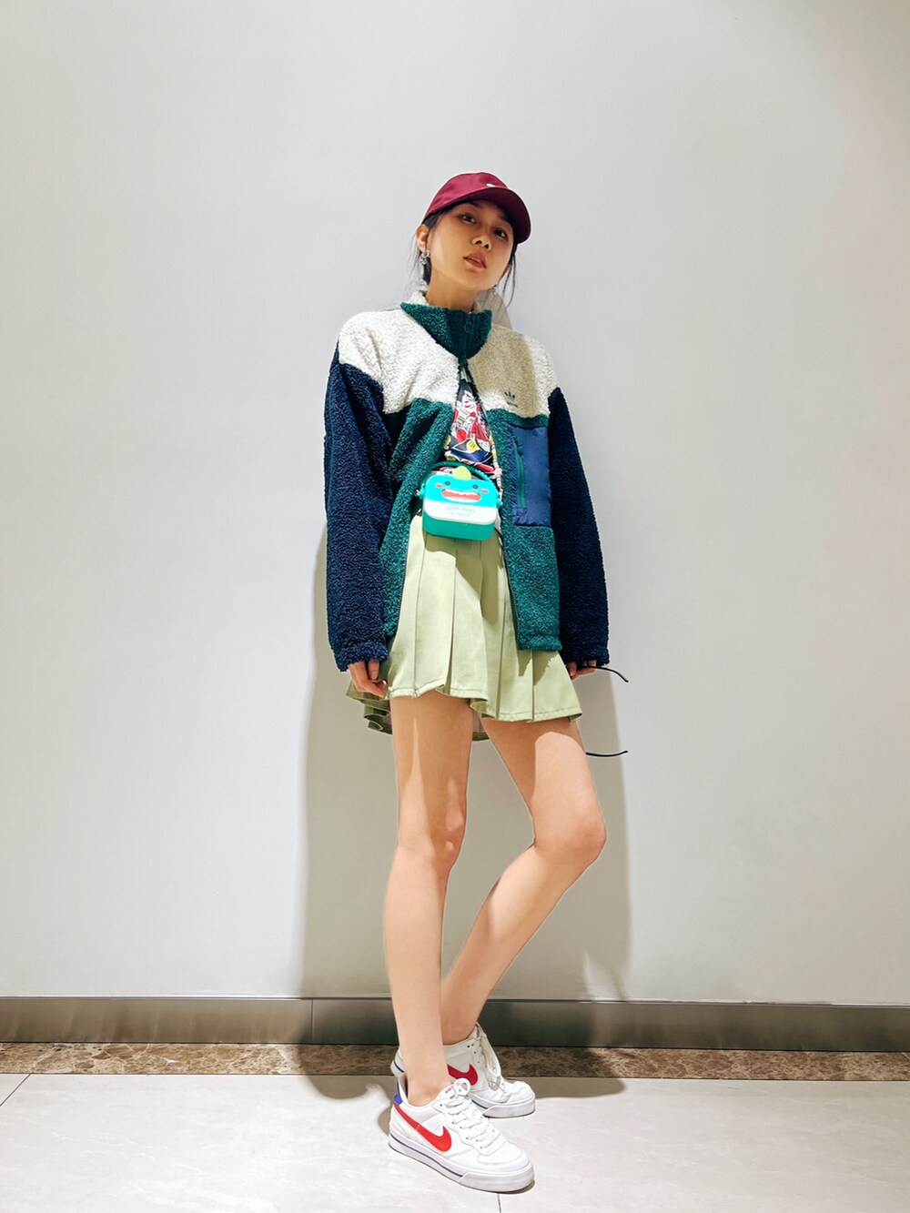 グリーン系のスタジャン、グリーン系のスカート、ホワイト系のスニーカーを着用したレディースの冬コーディネートの2枚目の写真