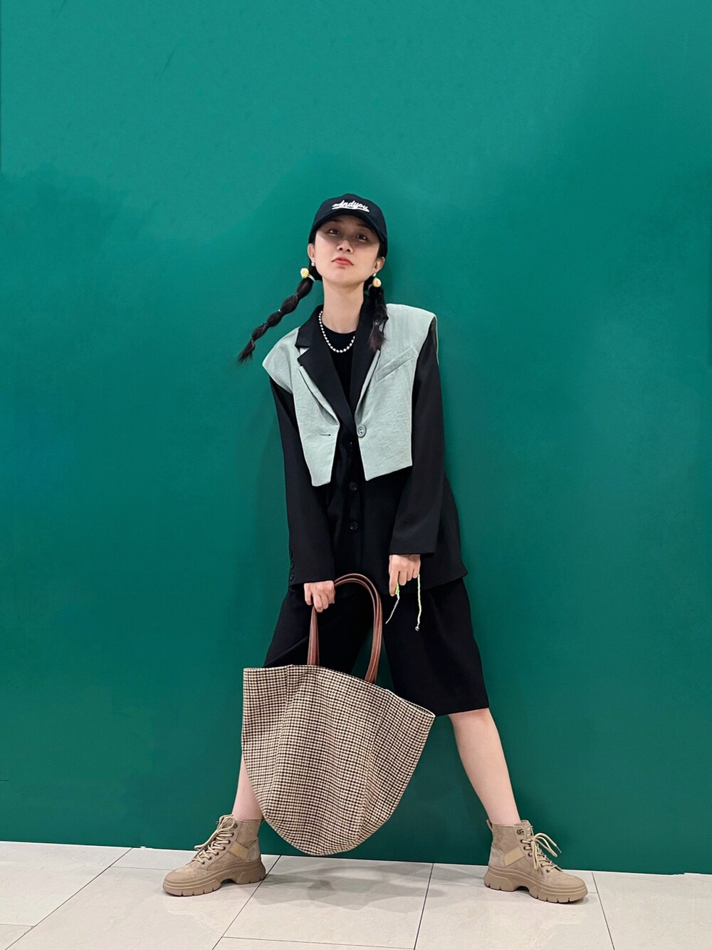 グリーン系のベスト、ブラック系のテーラードジャケット、ブラック系のカーゴパンツを着用したレディースの秋コーディネートの2枚目の写真