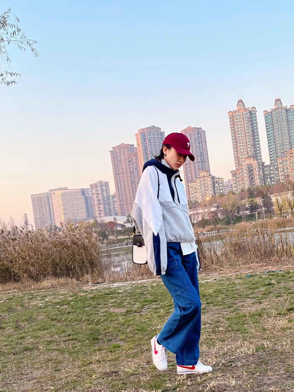 グレー系のパーカー、ブルー系のデニムパンツ、ホワイト系のスニーカーを着用したレディースの冬コーディネートの2枚目の写真