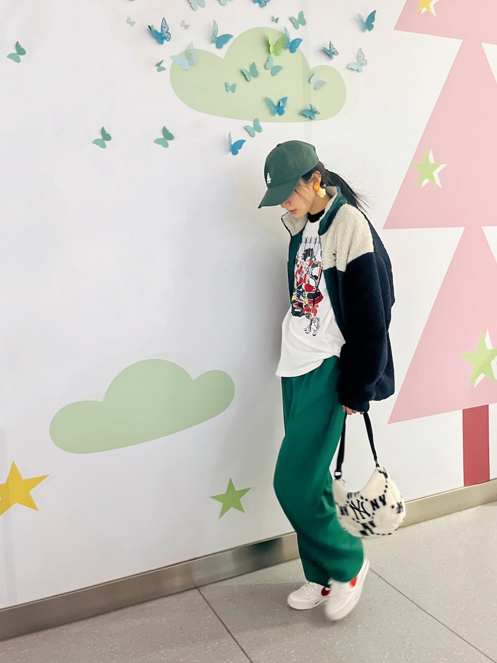 グリーン系のスタジャン、グリーン系のスラックス、ホワイト系のスニーカーを着用したレディースの冬コーディネートの2枚目の写真