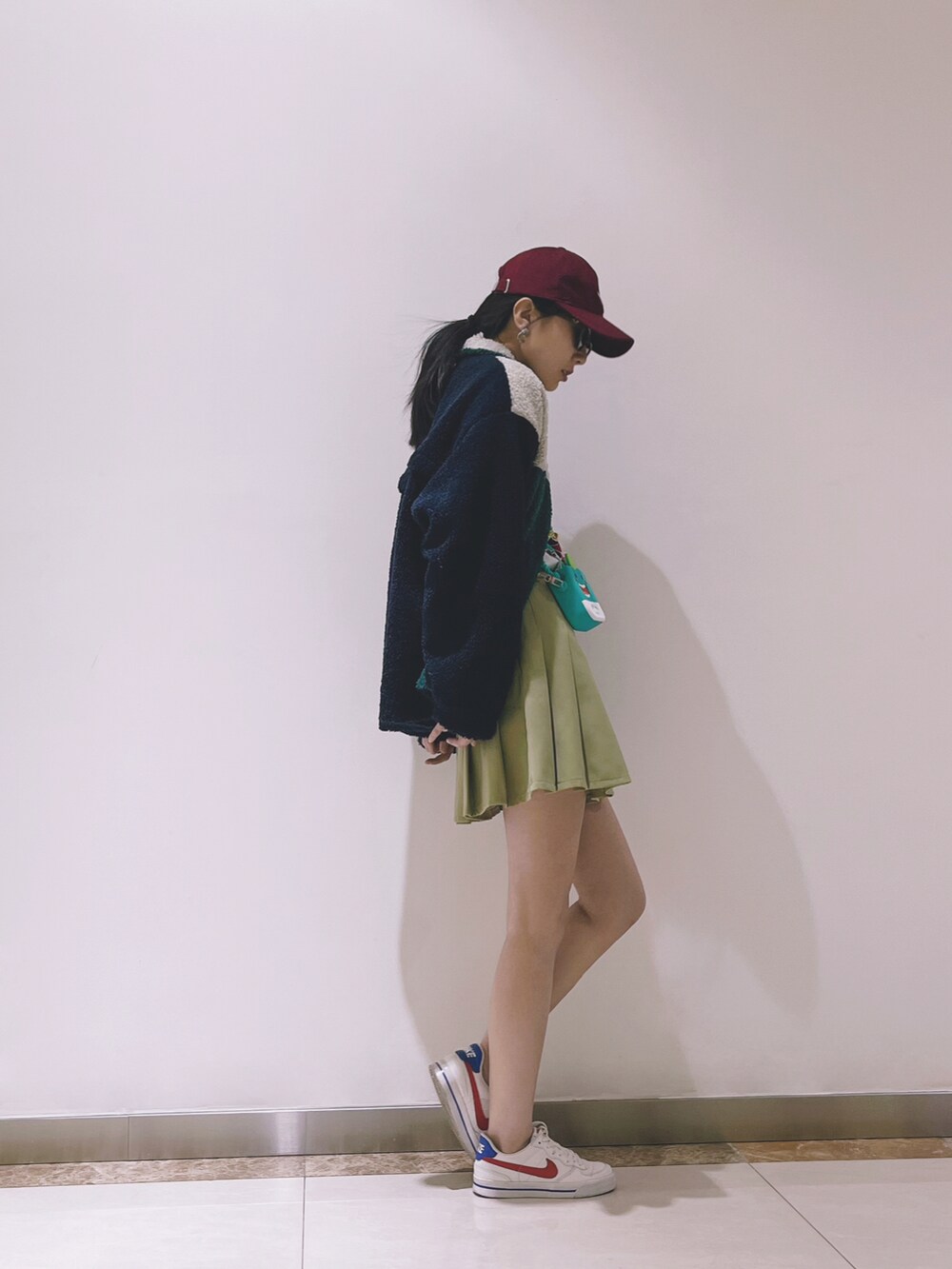 グリーン系のスタジャン、グリーン系のスカート、ホワイト系のスニーカーを着用したレディースの冬コーディネートの3枚目の写真