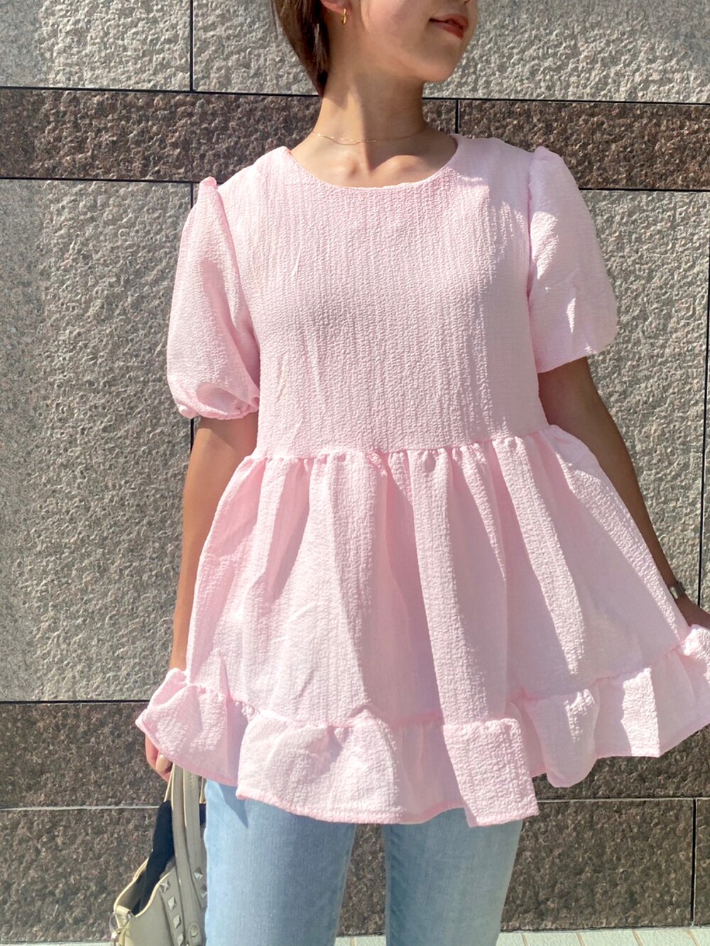 ピンク系のトップス、ブルー系のデニムパンツを着用したレディースの夏コーディネートの2枚目の写真