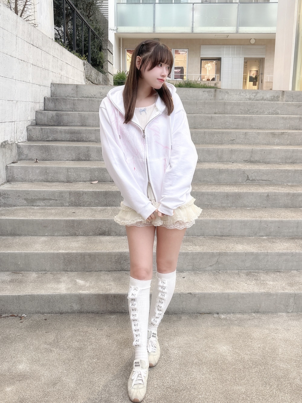 ホワイト系のパーカー、ホワイト系のスカート、ブルー系のスニーカーを着用したレディースの春コーディネートの2枚目の写真