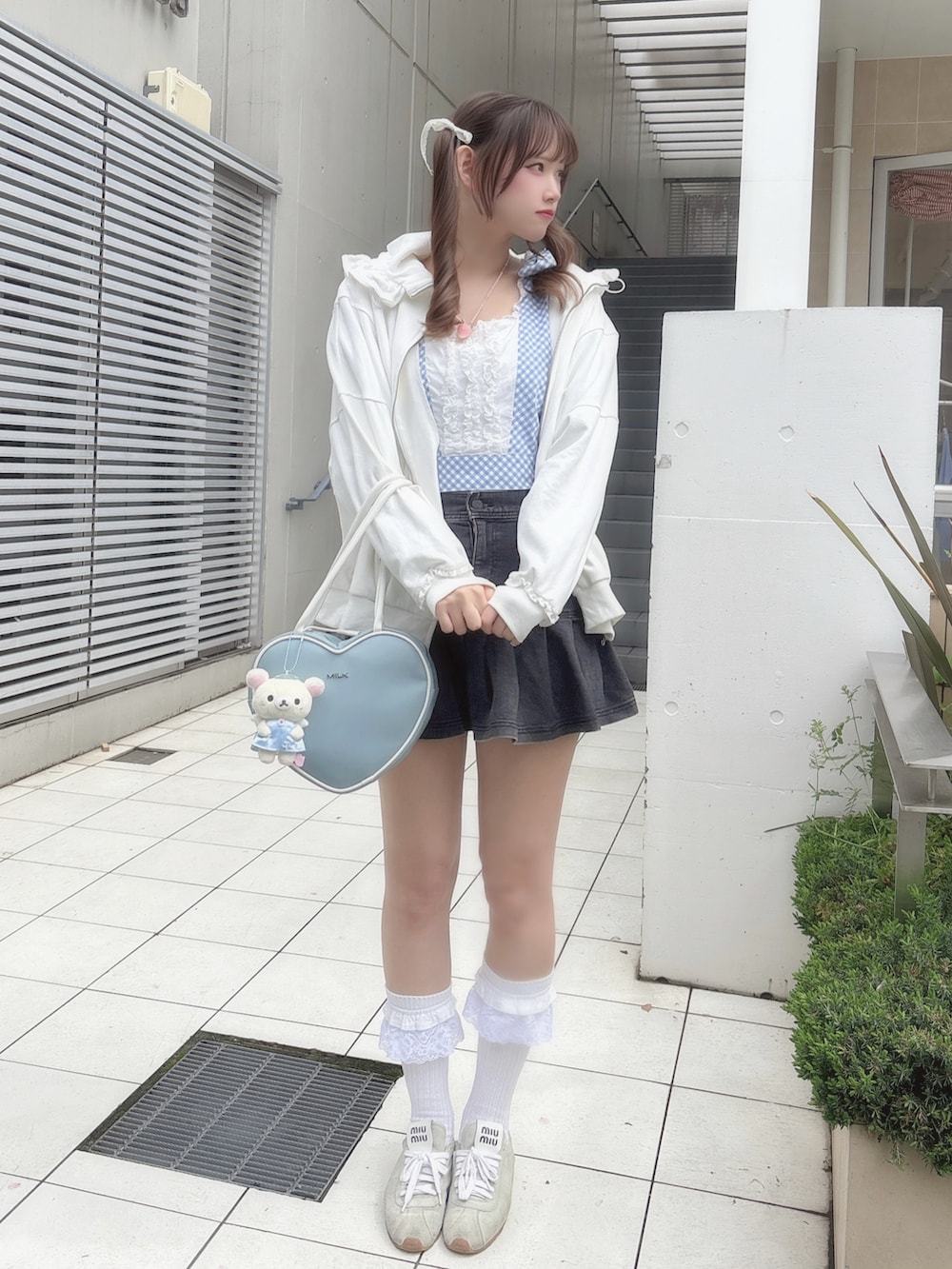 ブルー系のトップス、ホワイト系のパーカー、ブラック系のデニムスカートを着用したレディースの春コーディネートの2枚目の写真