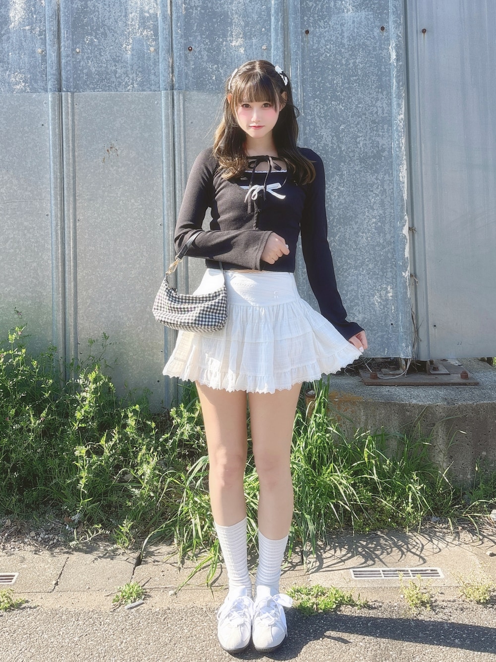 ブラック系のアンサンブル、ホワイト系のスカート、ブラック系のバッグを着用したレディースの春コーディネートの2枚目の写真