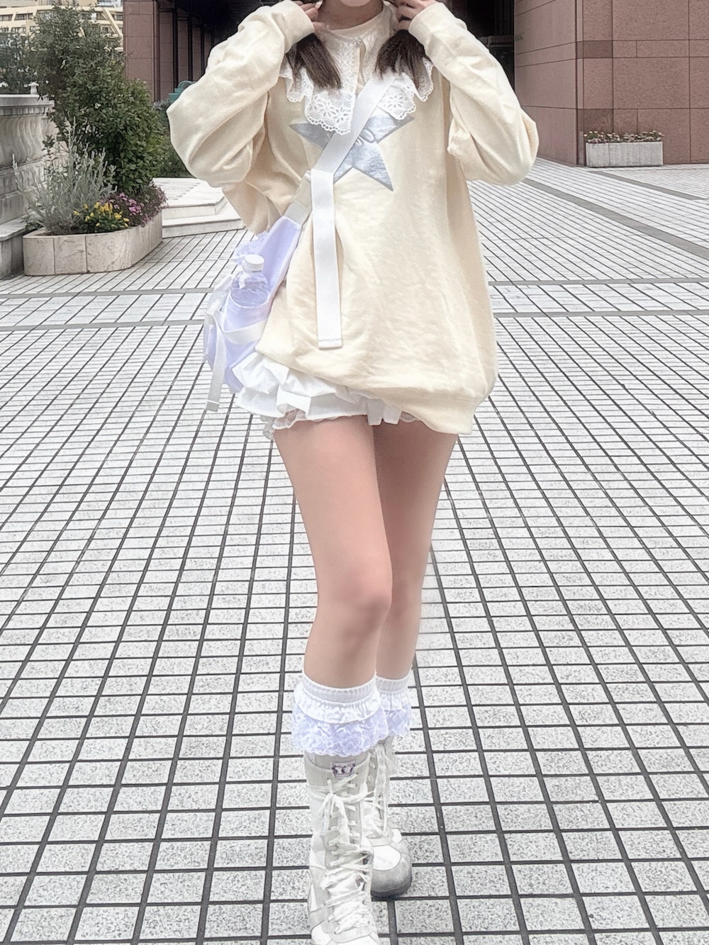 ホワイト系のスカート、ホワイト系のショルダーバッグ、イエロー系のスウェットを着用したレディースの春コーディネートの2枚目の写真