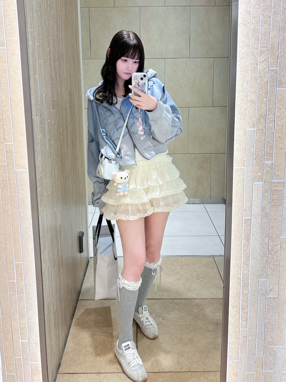 ブルー系のパーカー、ホワイト系のスカート、ブルー系のハンドバッグを着用したレディースの春コーディネートの2枚目の写真