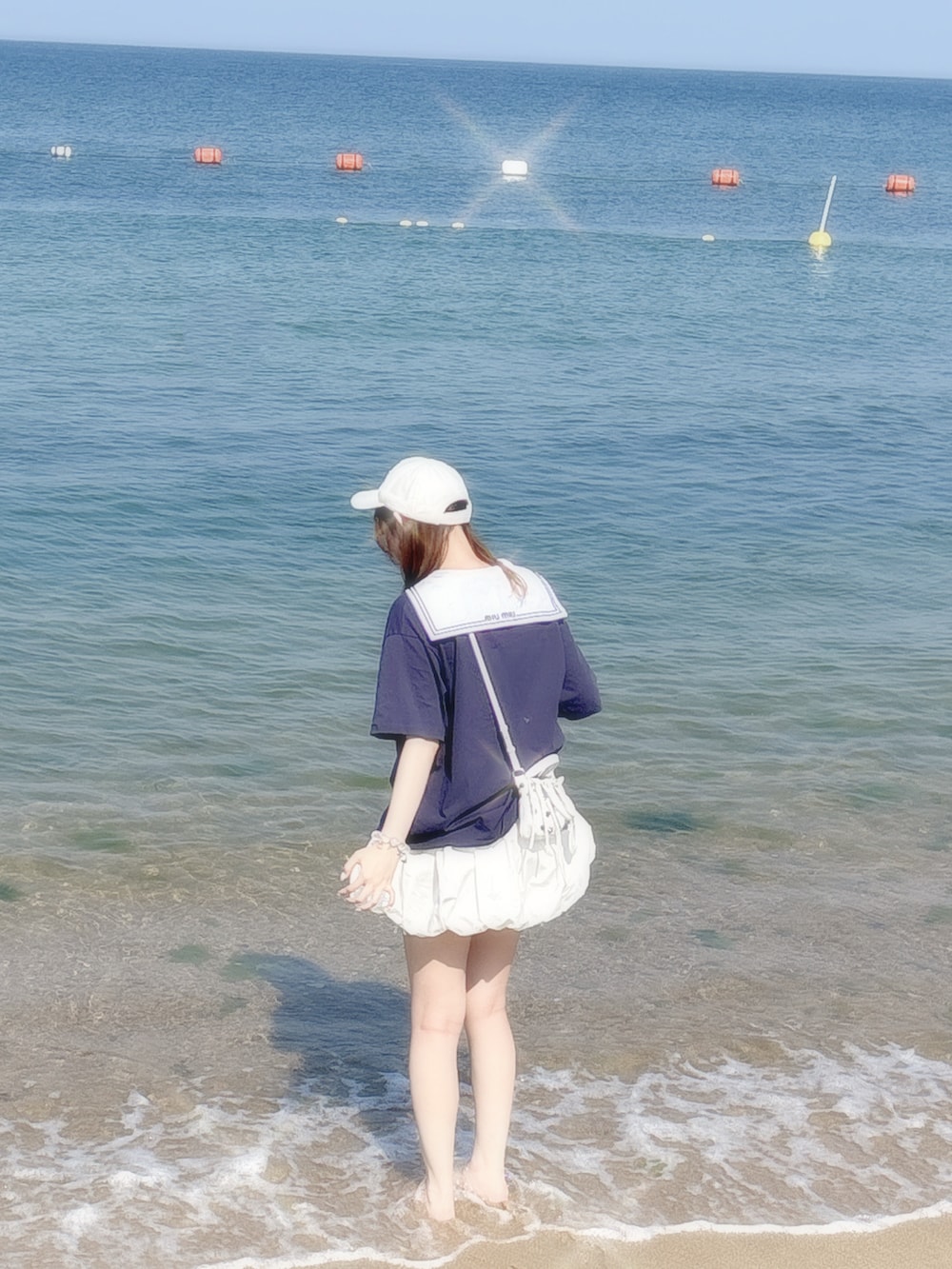 ブルー系のTシャツ/カットソー、ホワイト系のスカート、ホワイト系のショルダーバッグを着用したレディースの夏コーディネートの2枚目の写真