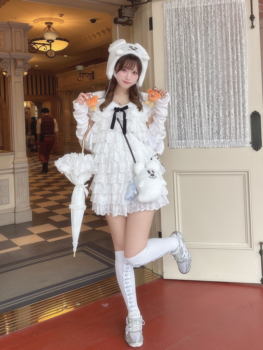 シルバー系のスニーカー、ホワイト系のワンピース、ホワイト系の長傘を着用したレディースの秋コーディネートの2枚目の写真