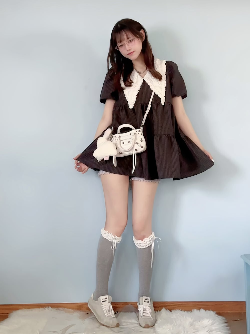 グレー系のワンピース、ホワイト系のカーディガン/ボレロ、ホワイト系のショルダーバッグを着用したレディースの春コーディネートの2枚目の写真