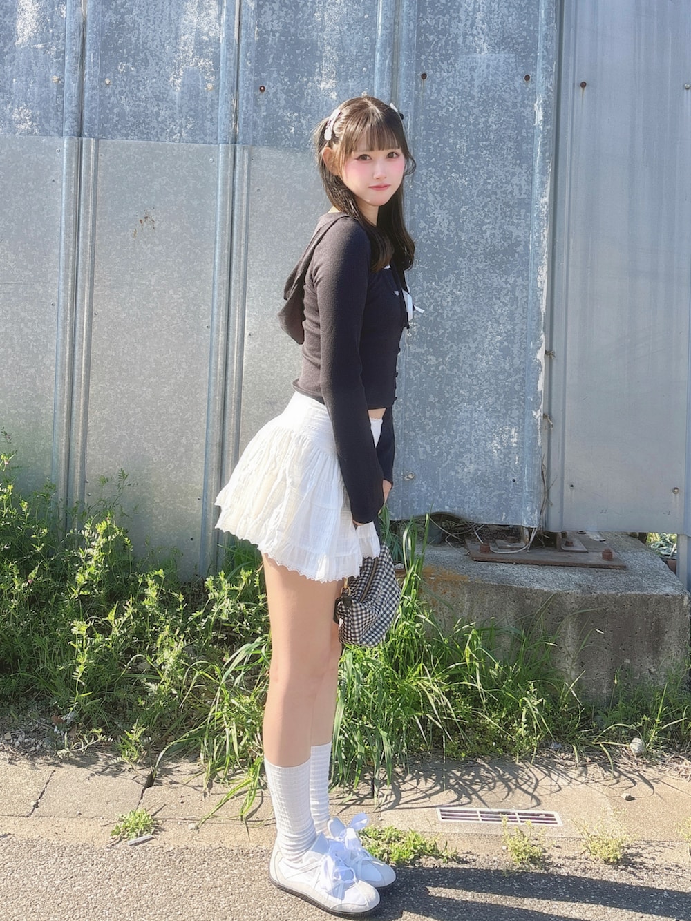 ブラック系のアンサンブル、ホワイト系のスカート、ブラック系のバッグを着用したレディースの春コーディネートの3枚目の写真