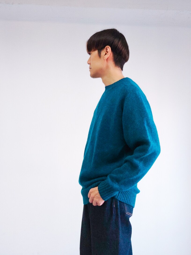 ブルー系のニット/セーター、ホワイト系のスニーカーを着用したメンズの秋コーディネートの2枚目の写真