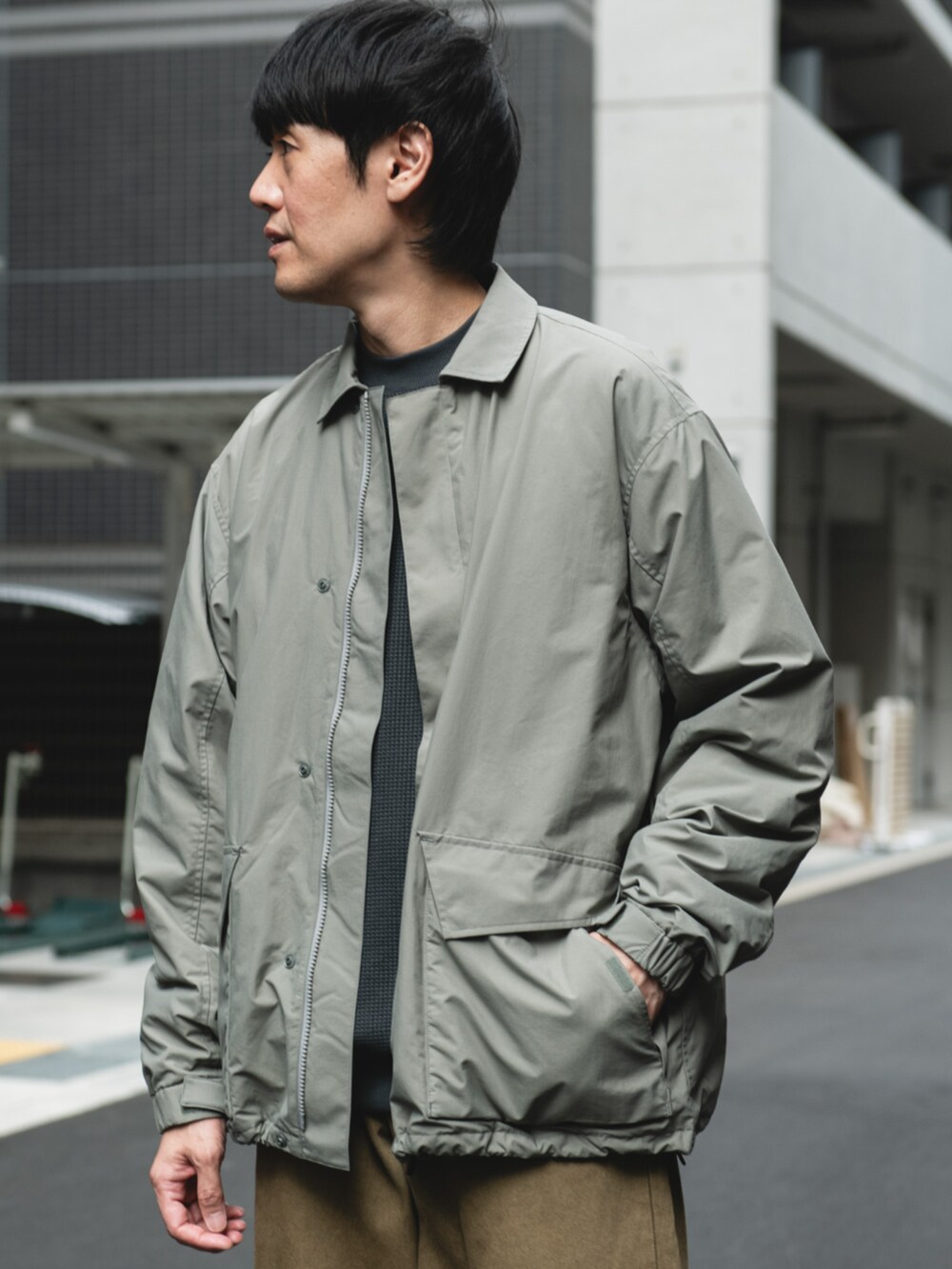 グリーン系のナイロンジャケットを着用したメンズの秋コーディネートの2枚目の写真