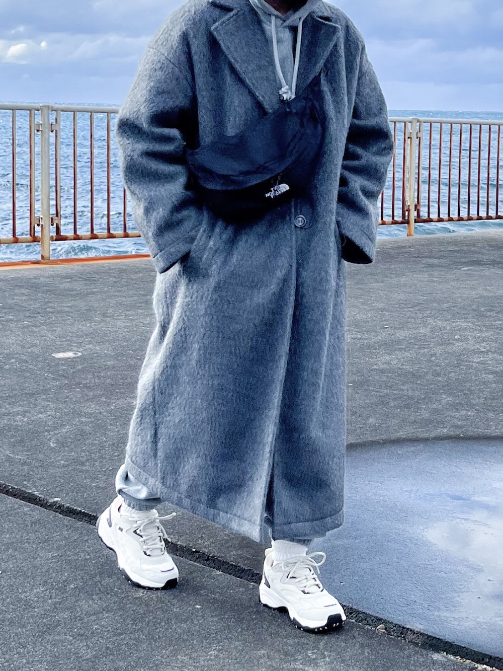 グレー系のチェスターコート、グレー系のパーカー、グレー系のスウェットパンツを着用したレディースの冬コーディネートの5枚目の写真