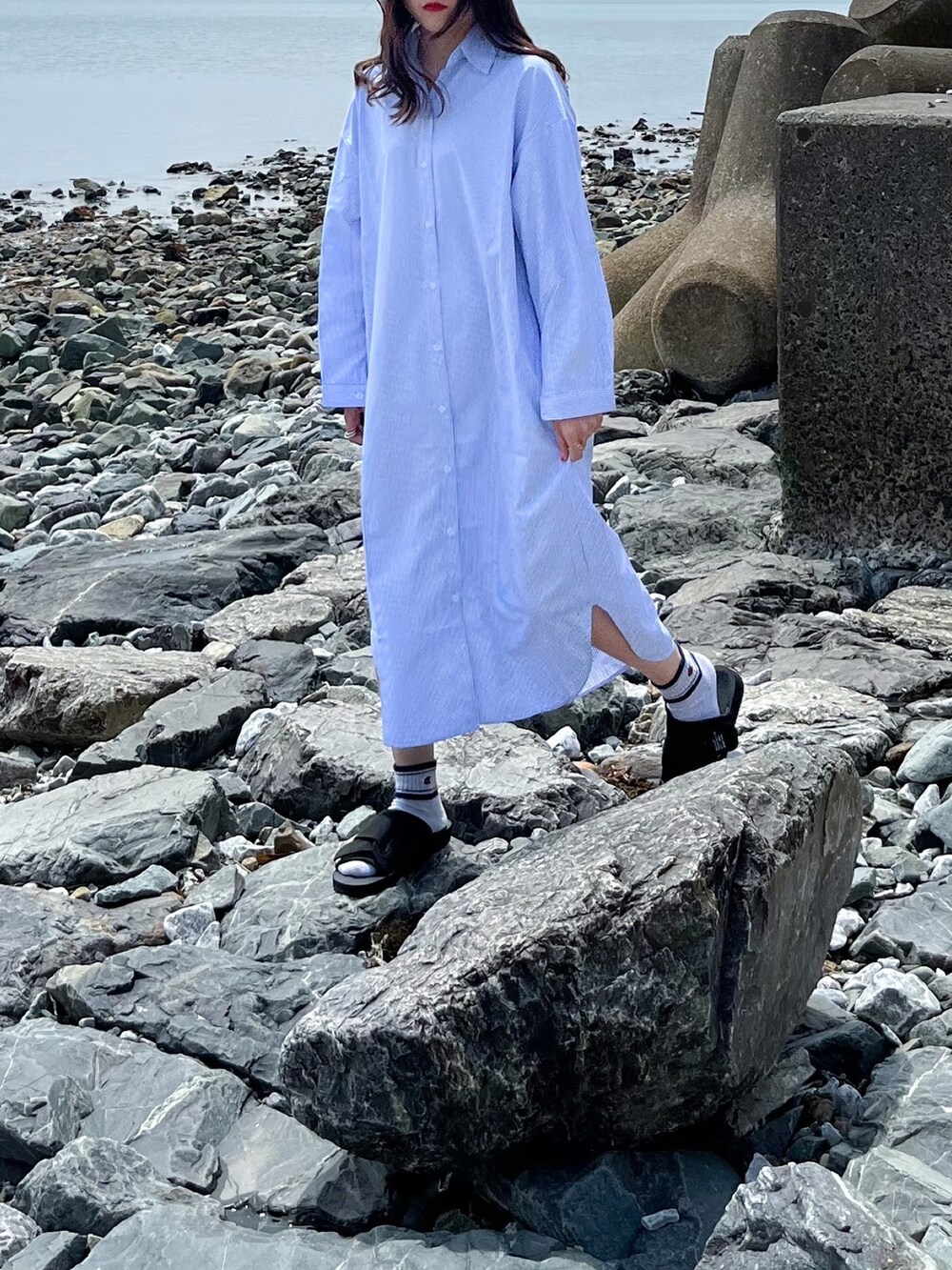 ブルー系のシャツワンピース、ブラック系のサンダル、ベージュ系のハットを着用したレディースの春コーディネートの2枚目の写真