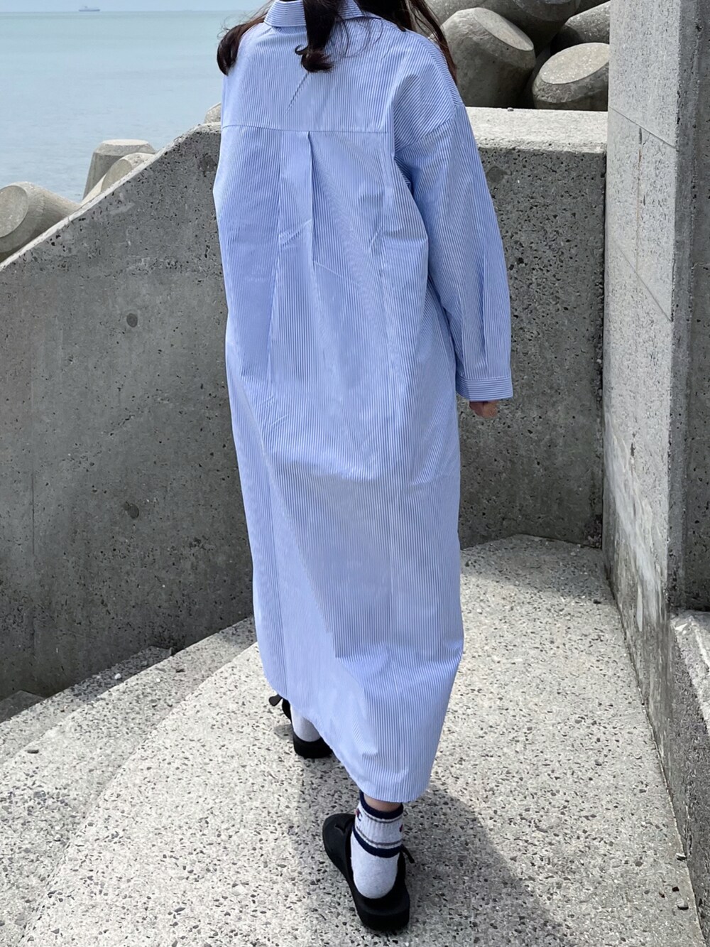 ブルー系のシャツワンピース、ブラック系のサンダル、ベージュ系のハットを着用したレディースの春コーディネートの3枚目の写真