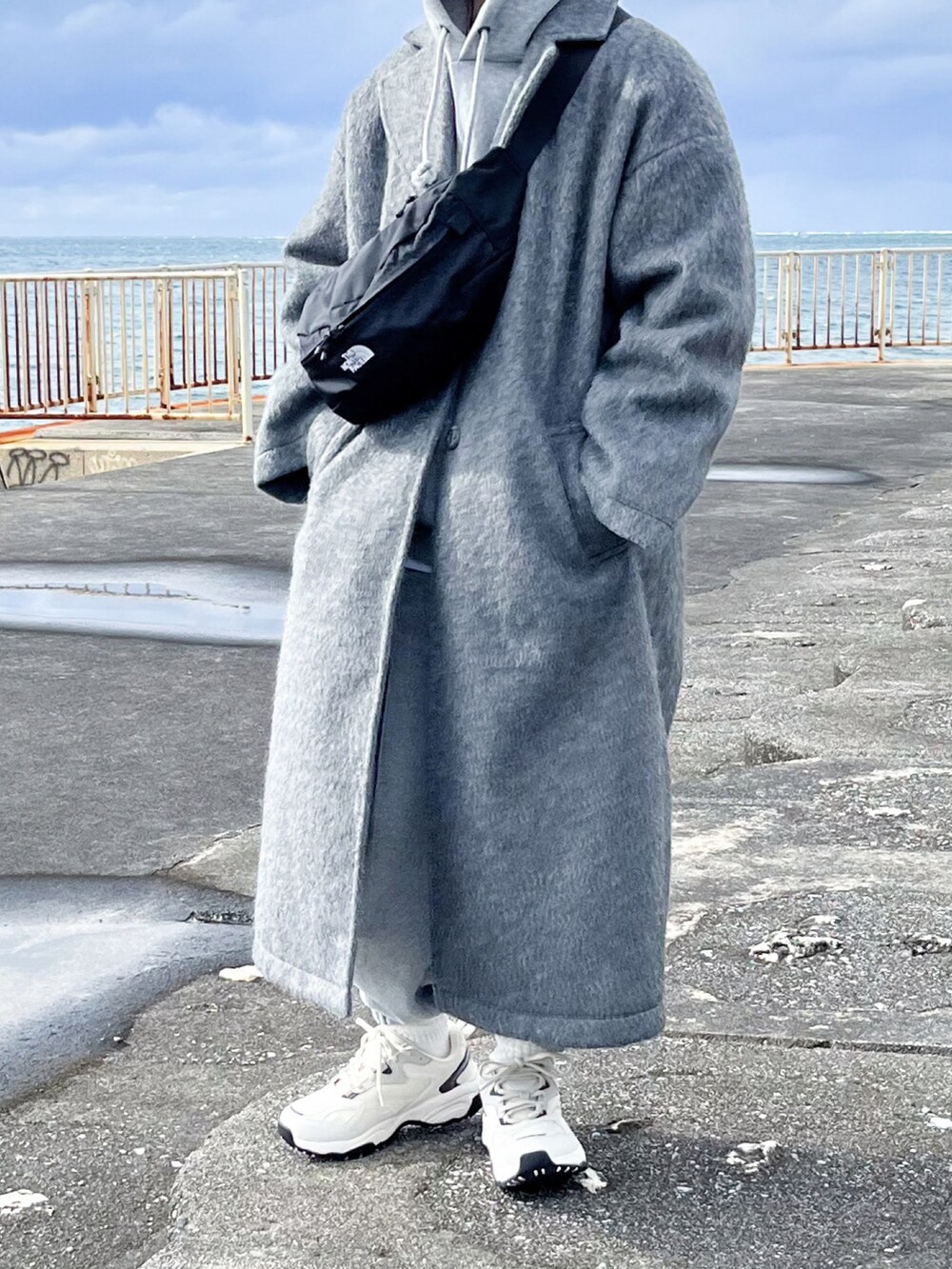 グレー系のチェスターコート、グレー系のパーカー、グレー系のスウェットパンツを着用したレディースの冬コーディネートの2枚目の写真