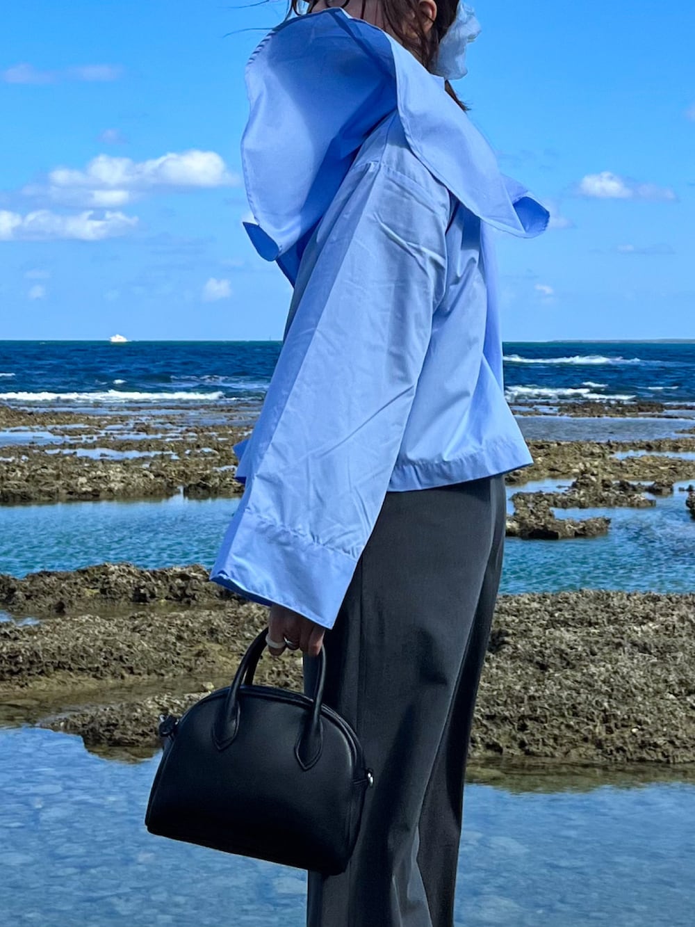 ブルー系のシャツ/ブラウス、グレー系のスラックス、ブラック系のボストンバッグを着用したレディースの秋コーディネートの2枚目の写真