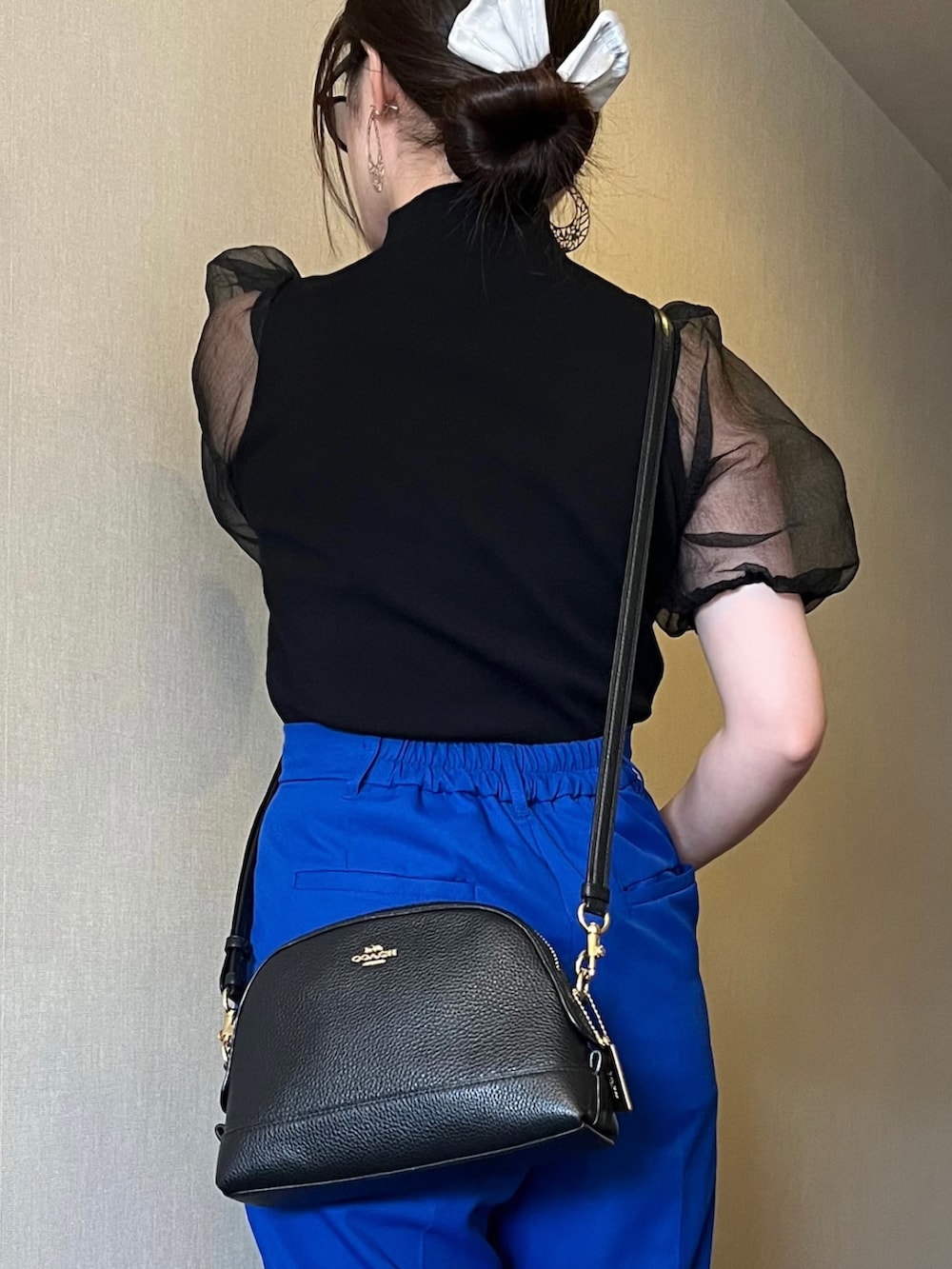 ブラック系のトップス、ブルー系のスラックス、ブラック系のショルダーバッグを着用したレディースの秋コーディネートの2枚目の写真