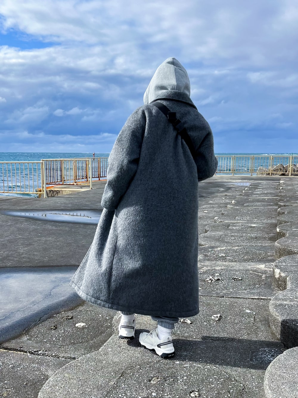 グレー系のチェスターコート、グレー系のパーカー、グレー系のスウェットパンツを着用したレディースの冬コーディネートの3枚目の写真