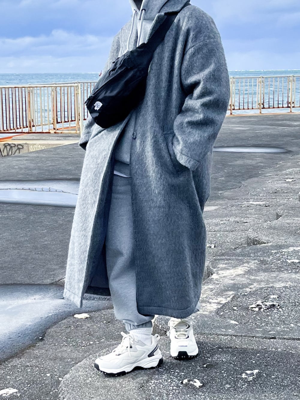 グレー系のチェスターコート、グレー系のパーカー、グレー系のスウェットパンツを着用したレディースの冬コーディネートの4枚目の写真