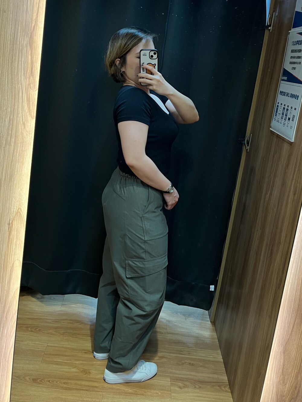 グリーン系のカーゴパンツ、ホワイト系のスニーカー、ブラック系のメッセンジャーバッグを着用したレディースの春コーディネートの3枚目の写真