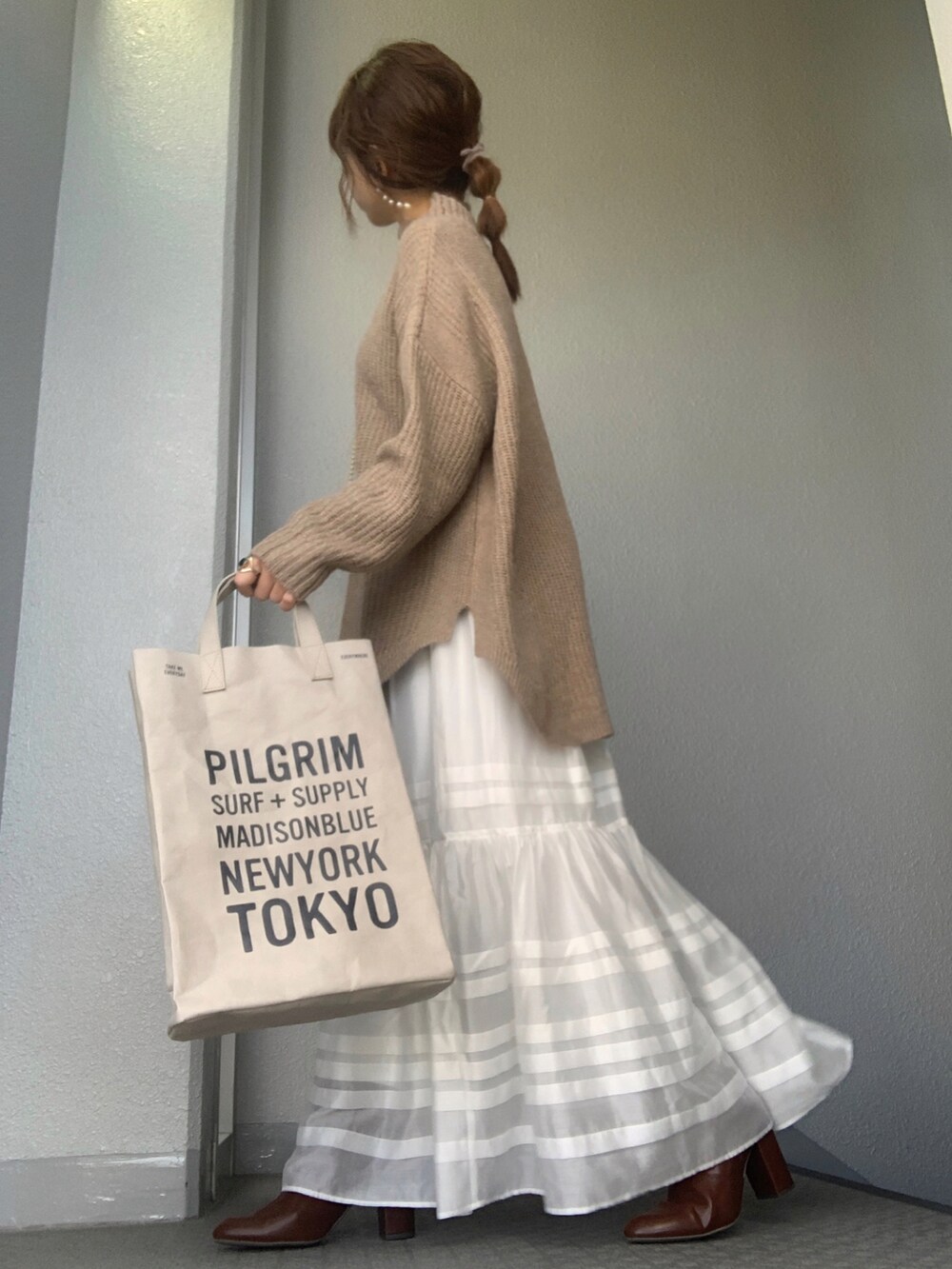 ブラウン系のニット/セーター、ホワイト系のスカート、ブラウン系のブーツを着用したレディースの冬コーディネートの2枚目の写真