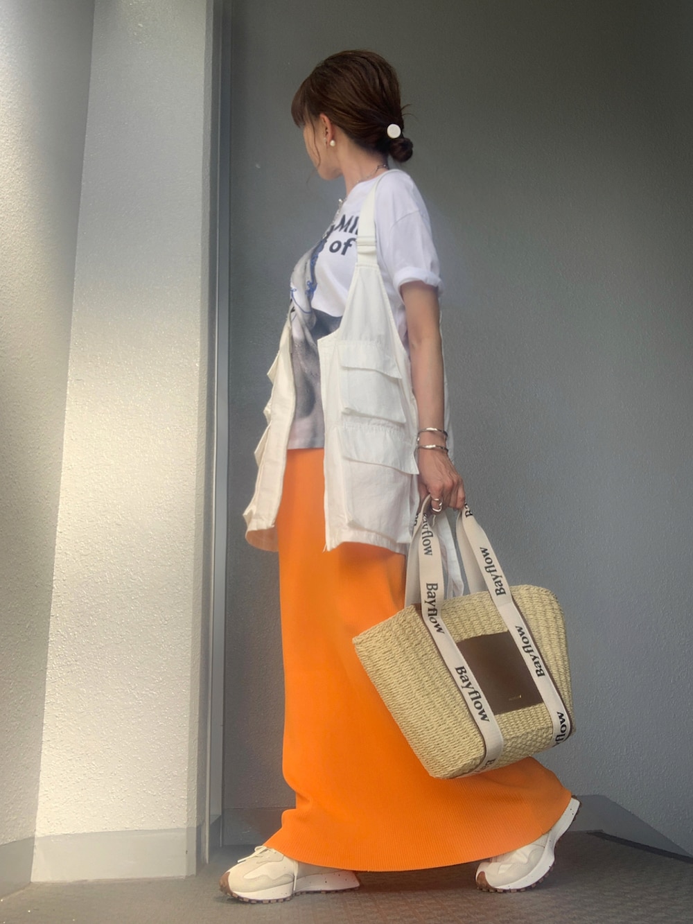 ベージュ系のトートバッグ、ホワイト系のベスト、ホワイト系のスニーカーを着用したレディースの春コーディネートの2枚目の写真