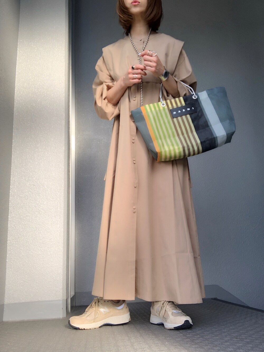 ベージュ系のシャツワンピース、その他のトートバッグ、ベージュ系のスニーカーを着用したレディースの春コーディネートの3枚目の写真