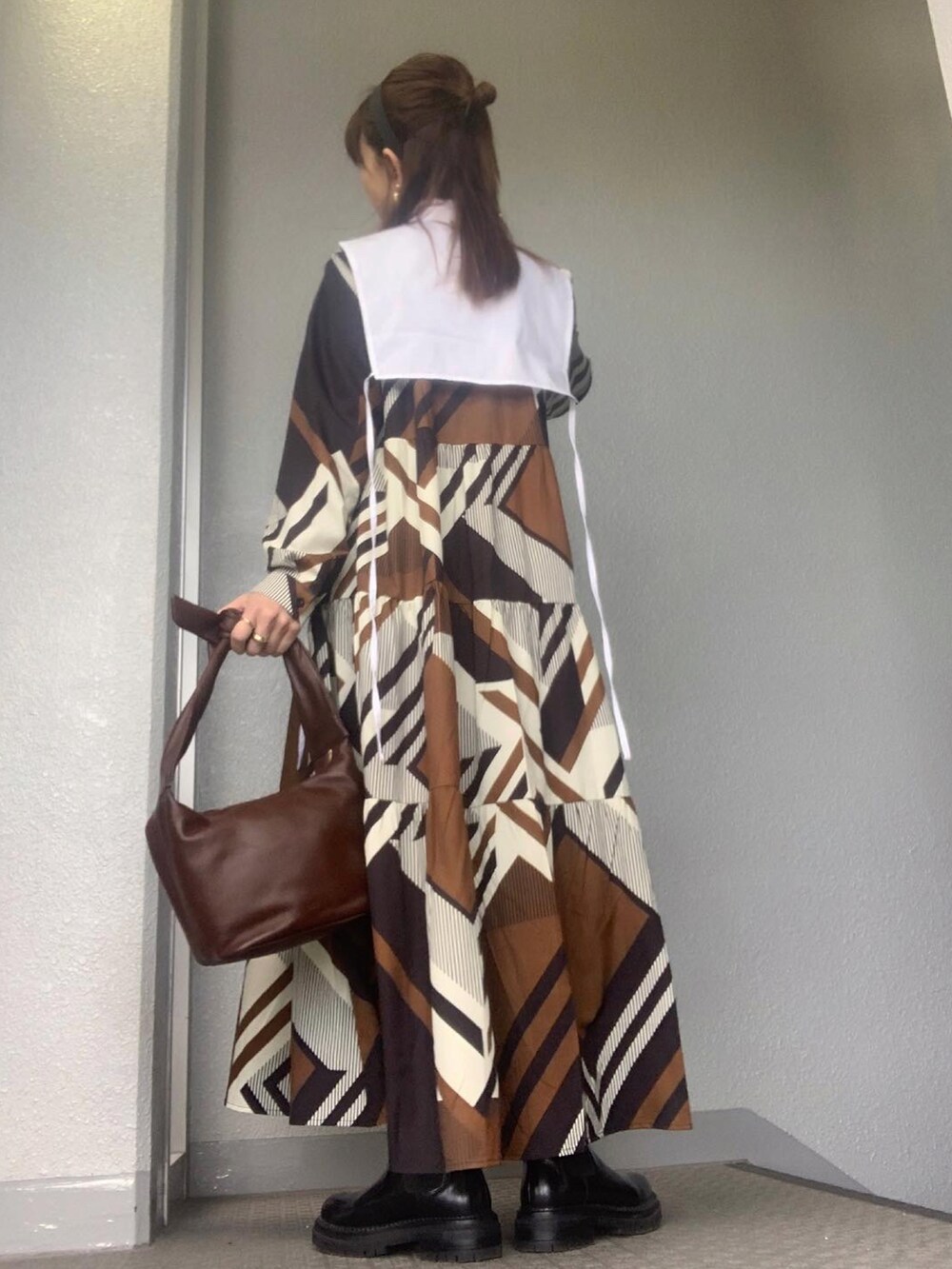 ブラウン系のワンピース、ホワイト系のシャツ/ブラウス、ブラウン系のバッグを着用したレディースの冬コーディネートの2枚目の写真